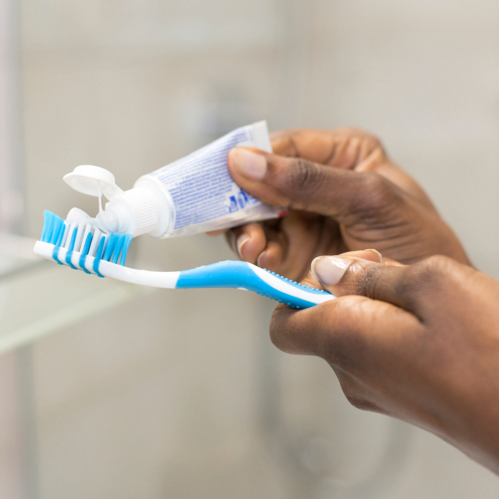 Persoon die tandpasta op een tandenborstel doet